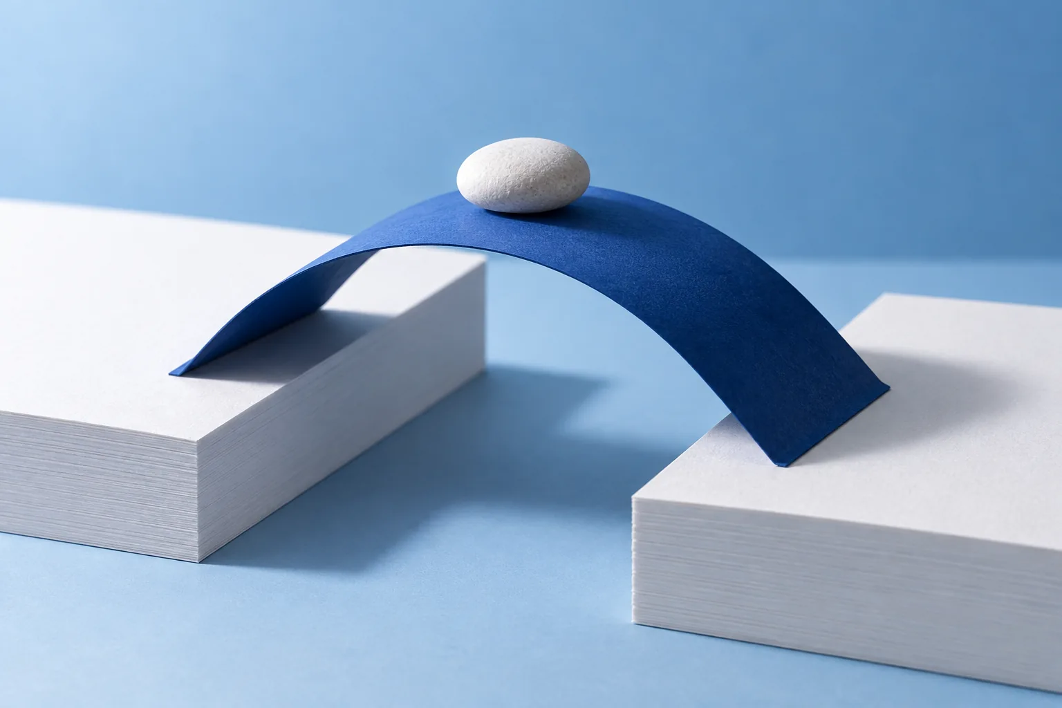 Un puente de papel azul une dos plataformas blancas separadas por un hueco