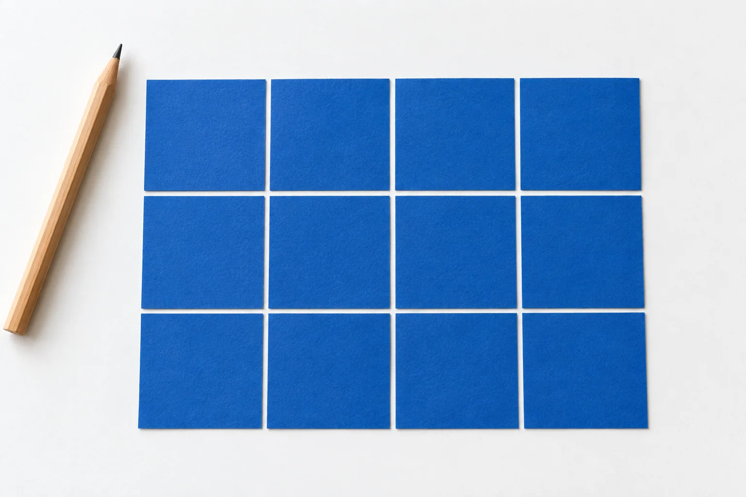 Twelve equal blue paper squares form a flat rectangle with four columns and three rows